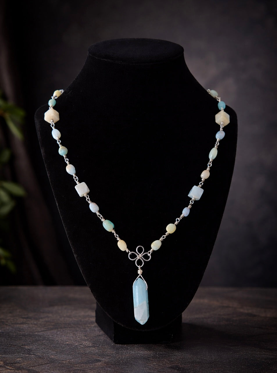 Necklace with a pendant on a black bust against a dark background
